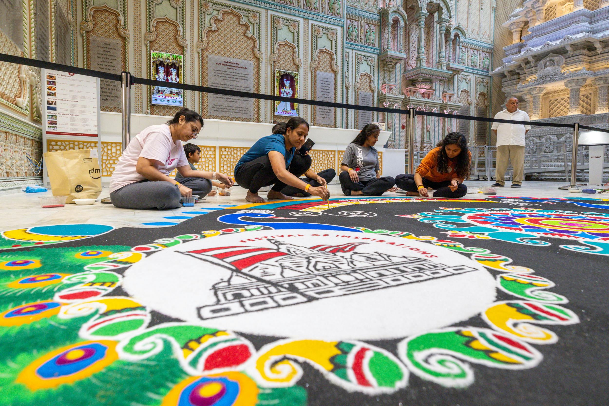 Volunteers diligently create a rangoli design to warmly welcome Swamishri