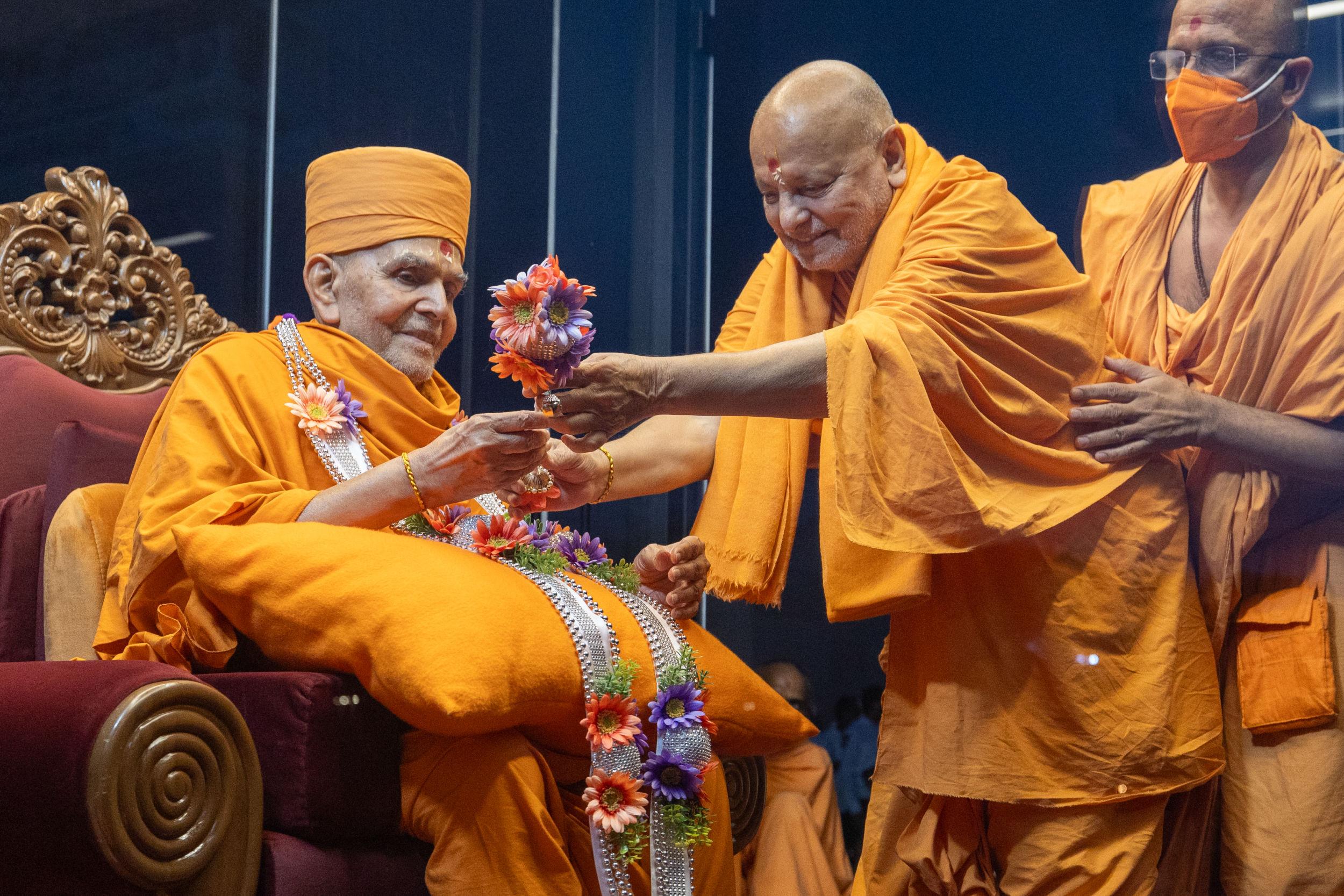 Sadguru Ishwarcharandas Swami presents Swamishri with a garland and chhadi